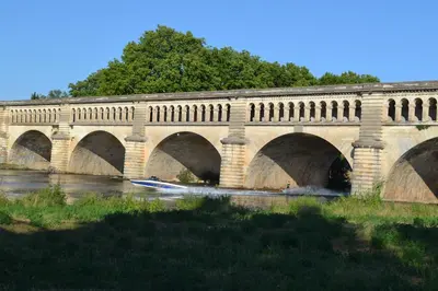 a bridge over a river with a boat in the water at L'instant Canal in Capestang