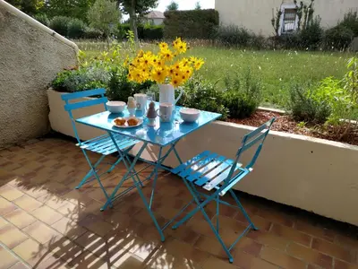 a blue table with two chairs and a vase of flowers at L'instant Canal in Capestang