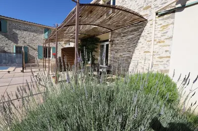 a stone building with an archway and some plants at Maison de Margot in Peyriac-Minervois