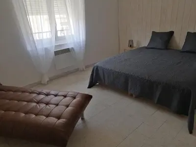 a bedroom with a bed and a couch and a window at La Maison CANTHEZ Wifi in Sigean