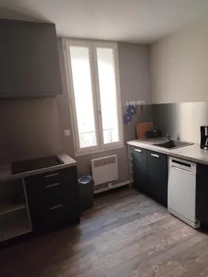 a kitchen with black and white cabinets and a window at La Maison CANTHEZ Wifi in Sigean