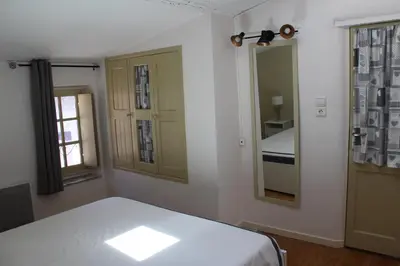 a white bedroom with a bed and a mirror at La Folie des Remparts in Carcassonne
