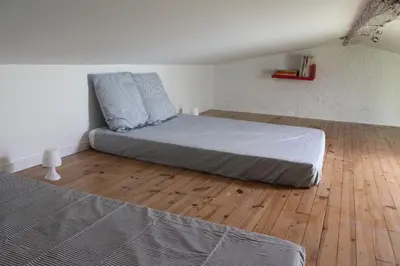 a bedroom with two beds and a wooden floor at La Folie des Remparts in Carcassonne
