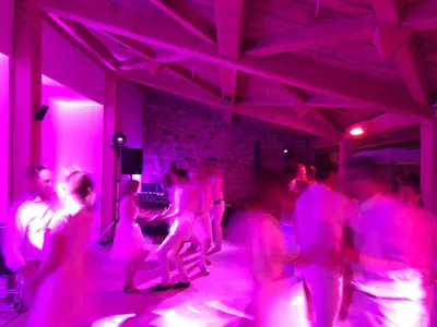 a group of people dancing in a room with purple lights at Domaine de Merlac in Rieussec