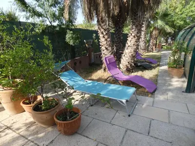 a patio with a table and chairs and palm trees at Lotus in Cébazan