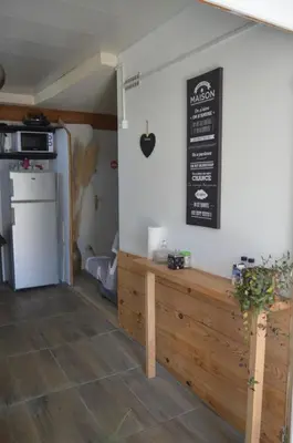 a kitchen with a table and a sign on the wall at El roble in LʼAiguillon