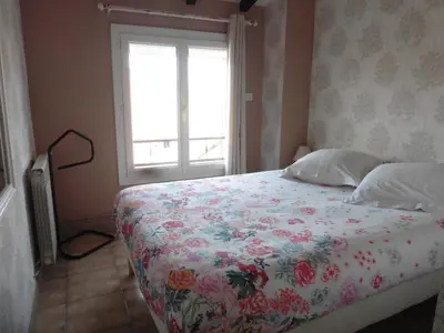 a bedroom with a bed with a floral bedspread and a window at gite echarou agréable maison de famille in Sigean