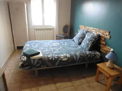 a bedroom with a bed with a blue wall at gite echarou agréable maison de famille in Sigean