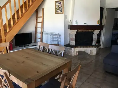 a living room with a wooden table and a fireplace at gite echarou agréable maison de famille in Sigean