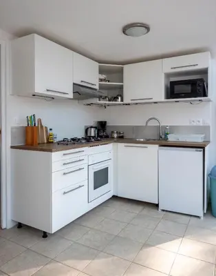 a white kitchen with white cabinets and appliances at Horizons Verts Appartement Jasmin in Puivert