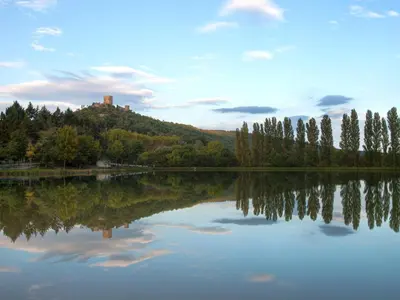 a lake with trees and a castle on a hill at Horizons Verts Appartement Jasmin in Puivert