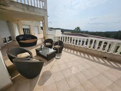 a balcony with chairs and a table on a building at La Pinède D'Estarac in Bages