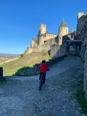 a person riding a bike in front of a castle at MAISON MIGNARDISE - Cité in Carcassonne