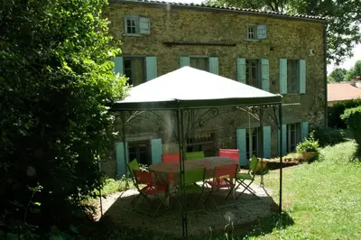 a table and chairs under an umbrella in front of a building at L'affable Les cammazes in Les Cammazes
