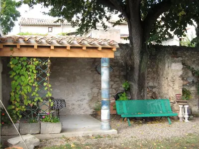 a green bench under a tree next to a wall at Chambre d'Hôtes la Poterie in Caunes-Minervois