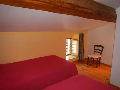 a bedroom with a red bed and a chair at Gite Le Lavoir - La Poterie in Caunes-Minervois