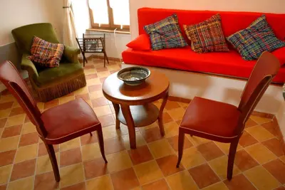 a living room with a red couch and chairs at Gite Le Lavoir - La Poterie in Caunes-Minervois