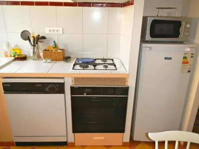 a small kitchen with a stove and a refrigerator at Gite Le Lavoir - La Poterie in Caunes-Minervois