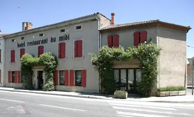 a white building with red shutters on a street at Logis Hôtels - Hôtel Restaurant du Midi in Revel