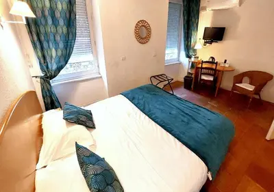 a bedroom with a bed and a table in it at Logis Hôtels - Hôtel Restaurant du Midi in Revel