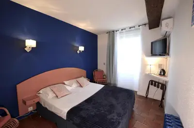 a bedroom with a bed with a blue wall at Logis Hôtels - Hôtel Restaurant du Midi in Revel