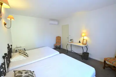 a bedroom with two beds and a table and a desk at Logis Hôtels - Hôtel Restaurant du Midi in Revel