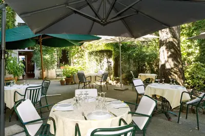 a group of tables and chairs under an umbrella at Logis Hôtels - Hôtel Restaurant du Midi in Revel