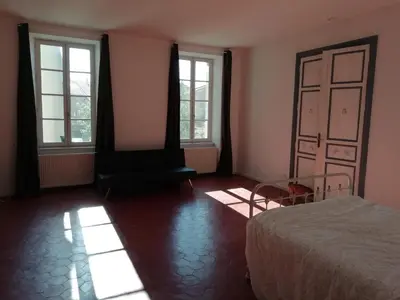 a bedroom with a bed and two windows at Les Colonnades in Moussan