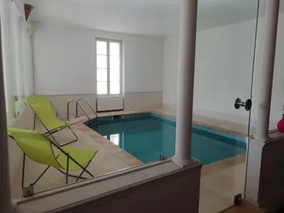 a pool with a green chair and a swimming pool at Les Colonnades in Moussan