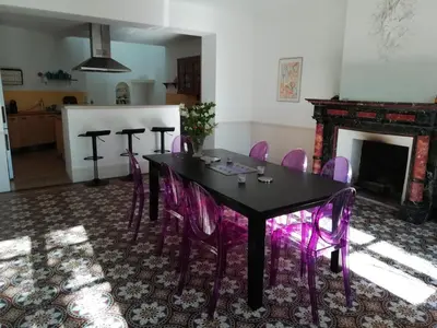 a dining room with a black table and purple chairs at Les Colonnades in Moussan