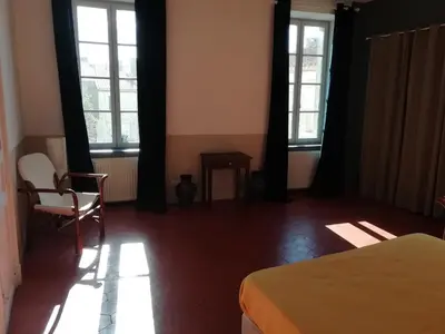 a bedroom with two windows and a bed and a chair at Les Colonnades in Moussan