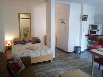 a bedroom with a bed and a kitchen with a microwave at Charmant studio centre ville Mirepoix in Mirepoix