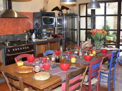 a kitchen with a wooden table with red bowls on it at Maison d'hôte la Tourette in Cucugnan