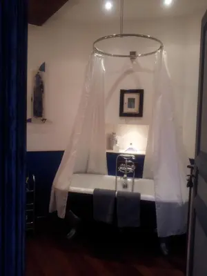 a bathroom with a tub with a white curtain at Maison d'hôte la Tourette in Cucugnan