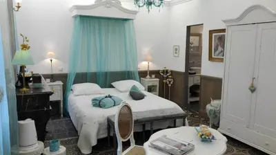a bedroom with a bed with blue pillows and a table at Maison d'hôte la Tourette in Cucugnan