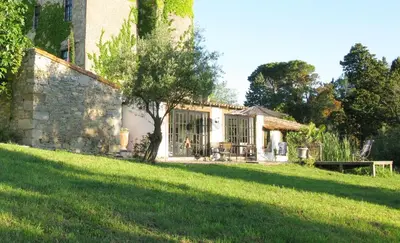 a restaurant with tables and chairs in a stone wall at Château de Villarlong in Villarzel-Cabardès