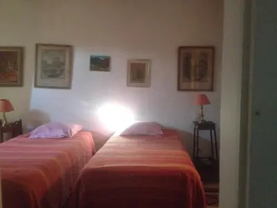 two beds in a room with a light on the wall at Sous l'abricotier in Durban-Corbières