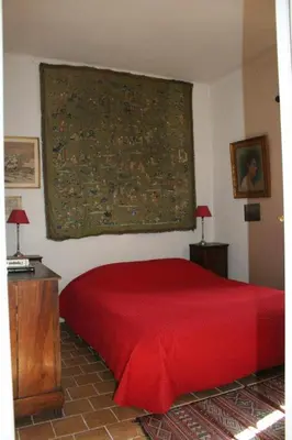 a bedroom with a red bed and a large painting on the wall at Sous l'abricotier in Durban-Corbières