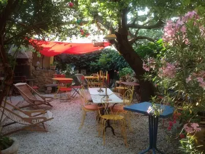a patio with tables and chairs under a tree at Sous l'abricotier in Durban-Corbières