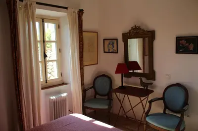 a bedroom with two chairs and a mirror and a bed at Sous l'abricotier in Durban-Corbières
