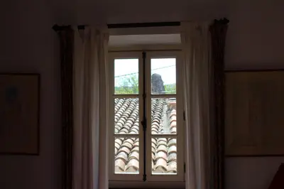 a window with curtains and a view of a building at Sous l'abricotier in Durban-Corbières