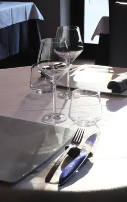 a table with two wine glasses and a blue knife and fork at Auberge du Cellier in Montner