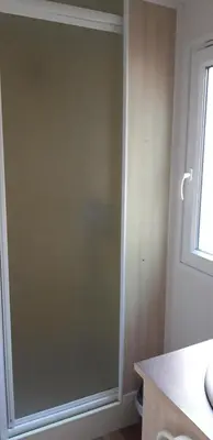 a glass shower door in a bathroom with a window at Camping la Source in Sournia