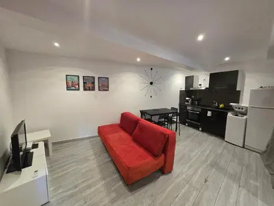 a living room with a red couch and a kitchen at T2 Cozy proche des Halles Climatisé in Narbonne