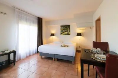 a hotel room with a bed and a table and a desk at Cerise Carcassonne Sud in Carcassonne