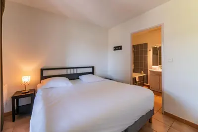 a bedroom with a large white bed and a bathroom at Cerise Carcassonne Sud in Carcassonne