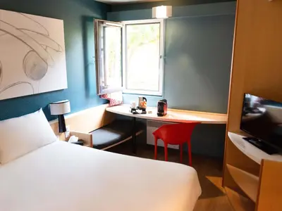 a bed with a pair of glasses and a bag on it at Hotel ibis Narbonne in Narbonne