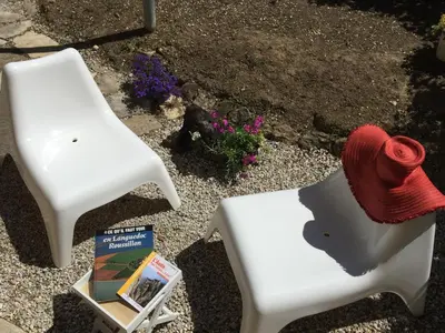 two white chairs sitting next to a book and a fire hydrant at Les iris in Carcassonne