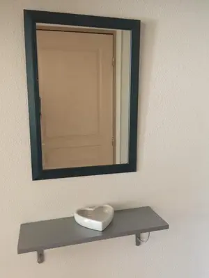a mirror on a wall with a shelf under it at Les iris in Carcassonne