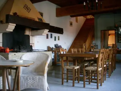 a dining room with tables and chairs and a kitchen at Chambres d'hôtes Domaine de Beaupré in Narbonne